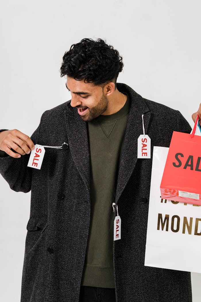 about-us Happy man holding shopping bags with sale tags, signaling retail discounts.